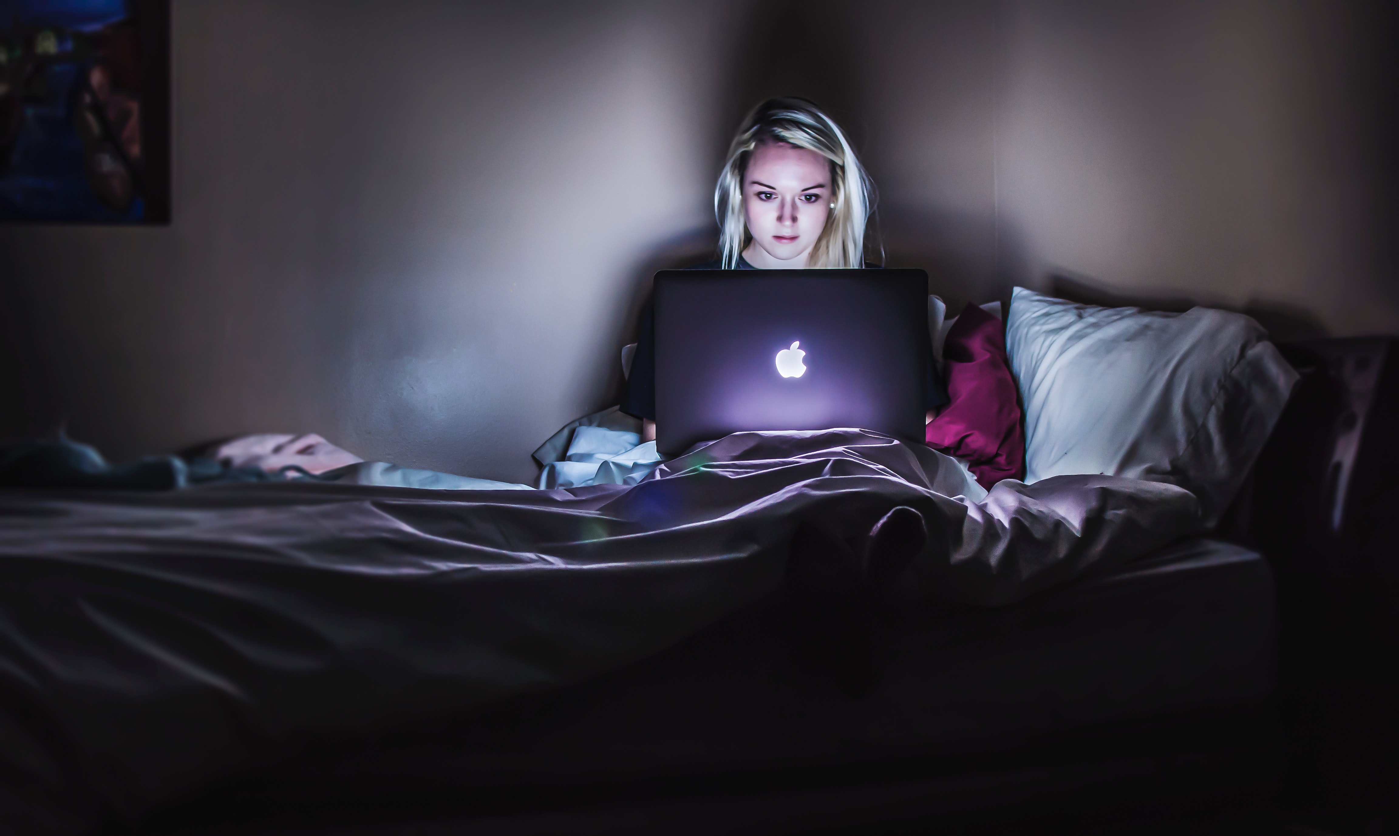 Woman working on computer in  bed